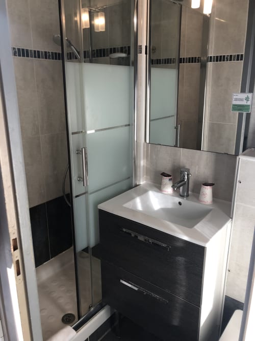 Modern bathroom with walk-in shower, black vanity, and white sink at Hôtel Maison Richet in Les Sables-d'Olonne