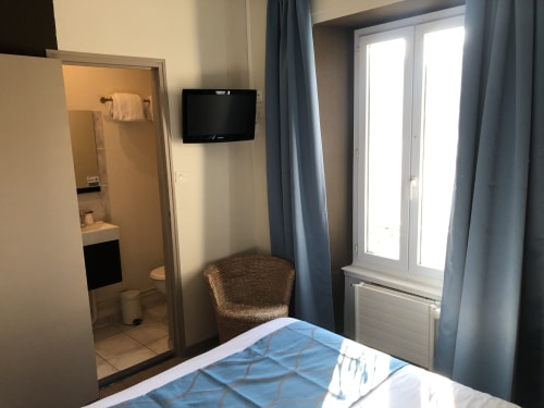Cozy double bedroom at Hôtel Maison Richet in Les Sables-d'Olonne with TV, bathroom, and balcony doors