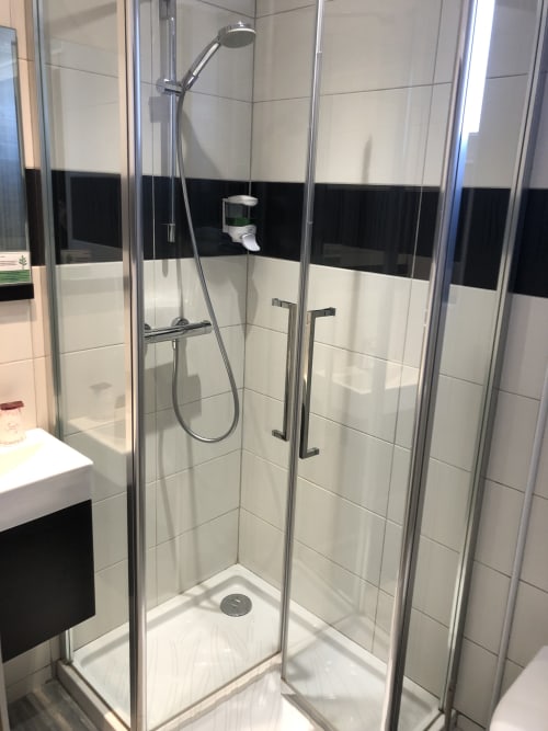 Modern glass shower enclosure with rainfall showerhead in Les Sables-d'Olonne hotel bathroom