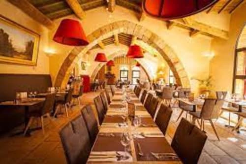 Salle à manger élégante aux voûtes cintrées du Gîte Sylvie CAMBON à Montséret, avec luminaires rouges et chaises en bois
