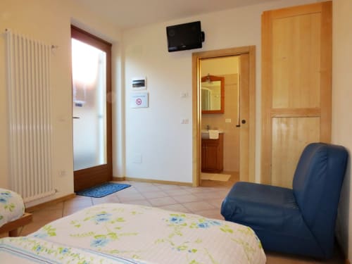 Camera doppia | Agritur Clementi, Trentino, azzurra, due letti singoli, Wifi gratuito, bagno privato con doccia, Tv, una comoda poltrona e mobilia in legno, portafinestra luminosa, balcone con ottima vista, appendiabiti, scrivania.
