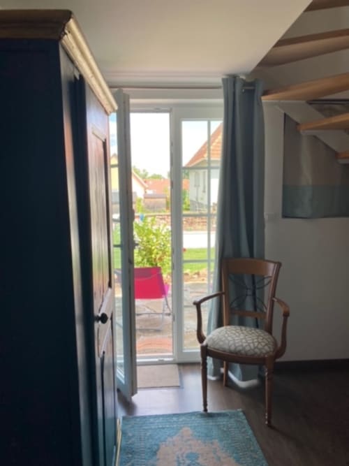 Chambre moderne du Gîte Le Clos d'Azel avec portes vitrées ouvrant sur une terrasse jardin et vue sur la campagne
