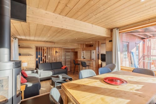 Modern wooden chalet interior with dining table, fireplace, and mountain views in Arc 1800 ski apartment, Bourg-Saint-Maurice