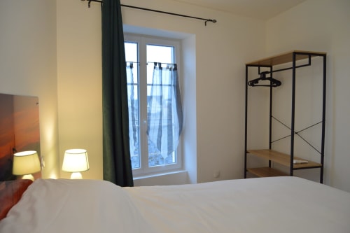 Modern bedroom at Locacharme cottage in Blois with river view, white bed, clothes rack, and bedside lamps