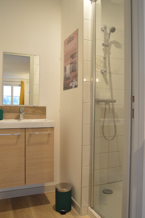 Modern bathroom in Locacharme cottage, Blois with wooden vanity, mirror, and walk-in shower with rainfall showerhead