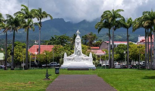 Monument blanc dans un parc bordé de palmiers avec montagnes, Saint-François Guadeloupe