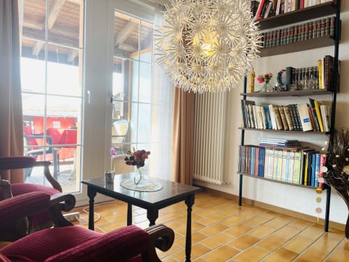 Elegant living room with burgundy armchairs, black coffee table, and shelving at Au P'tit Bonheur cottage in