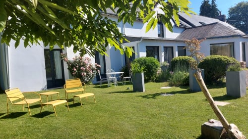 Jardin de Ty Coz Breizh, chambres d'hôtes situées à Lorient, Bretagne Sud, avec des fauteuils jaunes créant un contraste vibrant dans un espace verdoyant, et la maison d'hôtes en arrière-plan, offrant un cadre paisible et accueillant