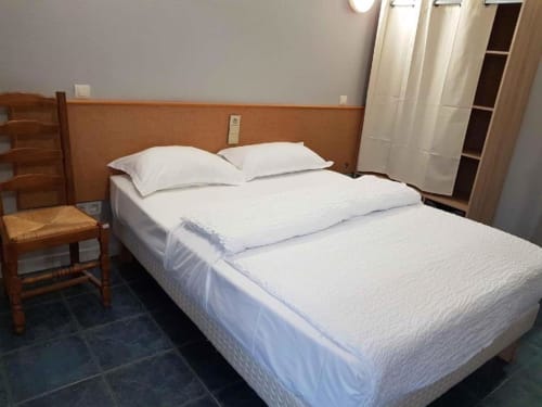 Llit doble amb llençols i coixins blancs en una habitació de bungalow de l'Hôtel Rocade, Pamiers