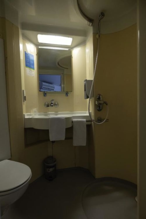 Bany modern al bungalow de l'Hôtel Rocade amb lavabo, mirall, dutxa i vàter a Pamiers