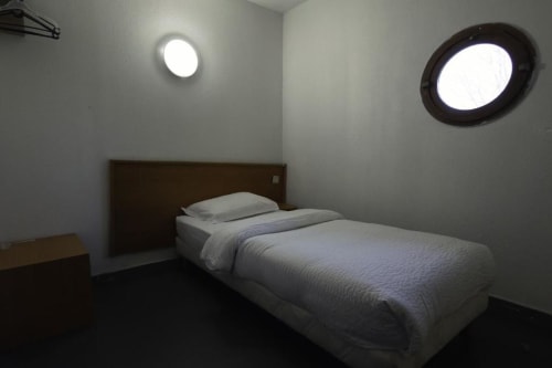 Llit individual en habitació Low Cost moderna de l'Hôtel Rocade, Pamiers amb finestres circulars i decoració minimalista