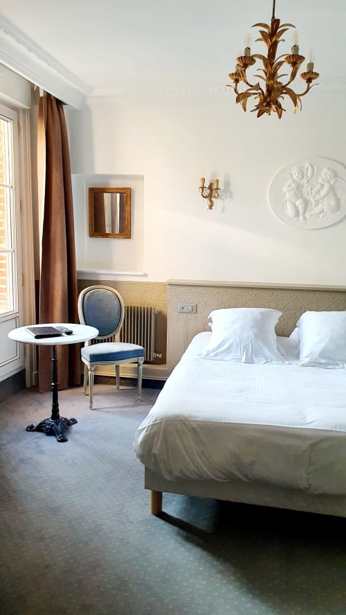 Chambre élégante à l'hôtel Les Cabines à Houlgate avec literie blanche, lustre doré ouvragé et décoration classique française