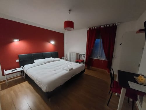 Chambre moderne au Comtois avec mur d'accent rouge, lit sombre, parquet et vue sur les montagnes en Saône, France