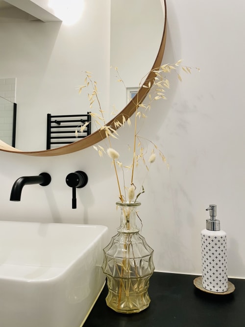 Modern bathroom at Maison Monsieur Léger in Montaut with curved mirror, black fixtures, white sink, and dried flowers in