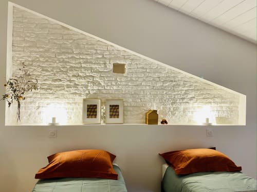 Alcôve confortable de la chambre du gîte Montaut avec mur en briques blanches, lits jumeaux aux oreillers cuivrés et étagère décorative