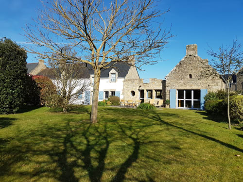 Hôtel Mer et Maisons à La Trinité-sur-Mer avec bâtiments en pierre et blanc, pelouse impeccable et arbre nu sous ciel bleu