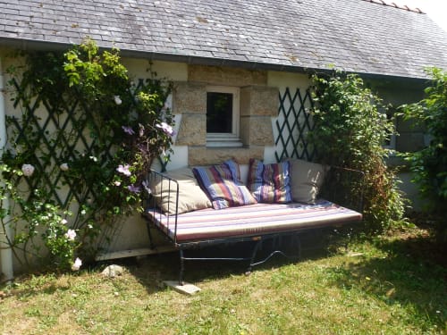Lit de jour confortable aux coussins rayés, niché dans un jardin fleuri à Mer et Maisons, La Trinité sur Mer