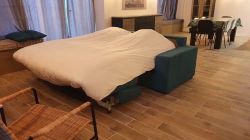 Open sofa bed with cream bedding in Locacharme cottage Blois, featuring green armrests and wooden flooring