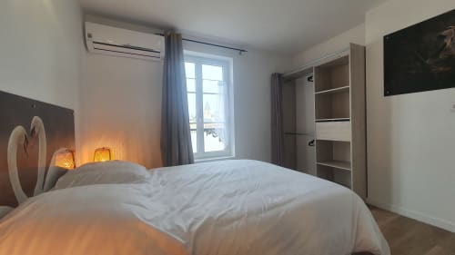 Modern bedroom at Gîte Des Cygnes in Blois with white bed, ambient lighting, and river view window