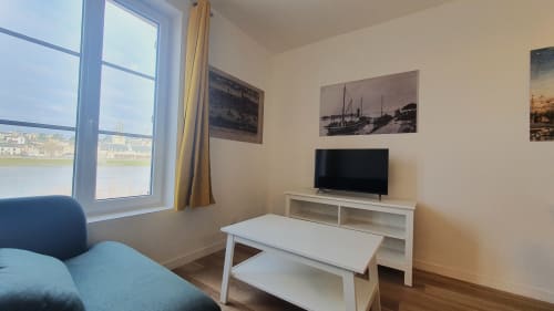 Modern cottage living room in Blois with river view, flat screen TV, white furniture, and Loire Valley scenery through large