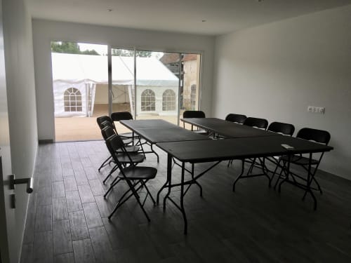 Salle de réunion moderne au Domaine Des Bois Argentés avec tables, chaises et vue sur la terrasse à Pruniers-en-Sologne