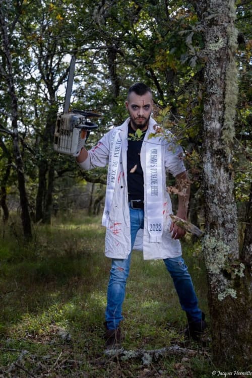 Homme en blouse blanche tenant une tronçonneuse en forêt près du Domaine Des Bois Argentés, Pruniers-en-Sologne