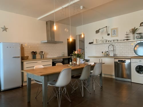 Cuisine cottage moderne avec table à manger, appareils en acier inoxydable et luminaires suspendus aux Filles du Bord de Mer