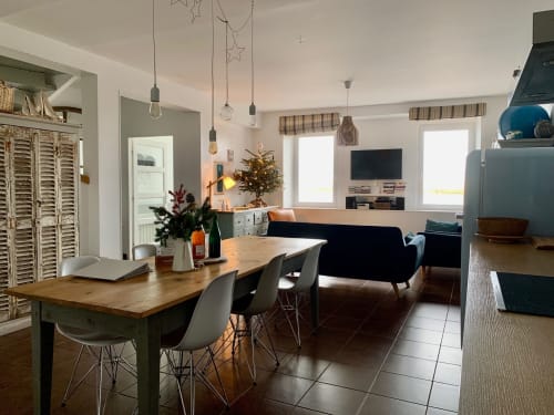 Séjour ouvert avec table à manger, canapé noir, télévision et vue sur mer aux Filles du Bord de Mer, Port-en-Bessin.