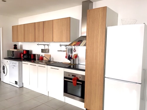 Cuisine moderne dans l'appartement Rouge Canneberge à Couleurs Montagne, Valloire, avec meubles en bois, électroménagers blancs et noir