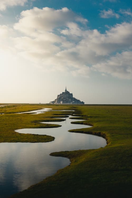 Het kasteel van Mont-Saint-Michel rijst boven de getijdenmoerassen uit met kronkelende waterwegen in de buurt van Normandië, Frankrijk
