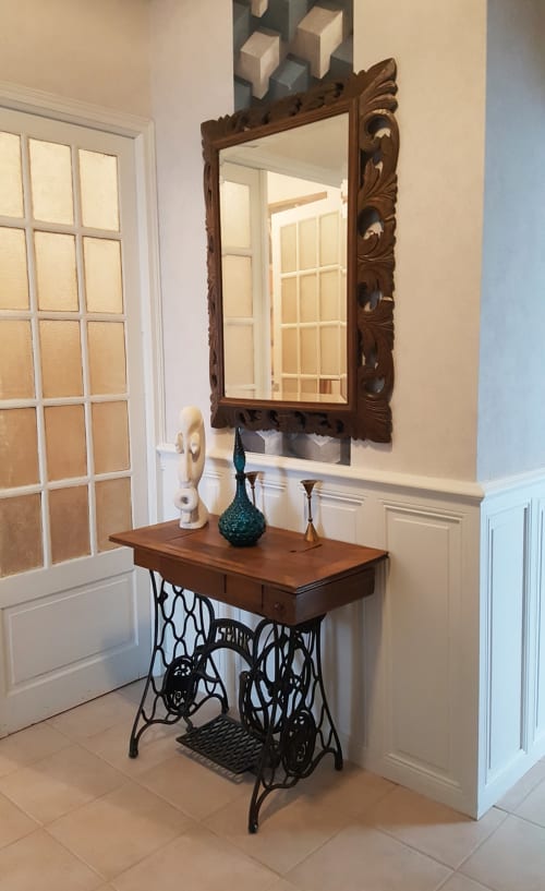 Entrée élégante aux Forges Du Lou avec miroir en bois ouvragé, table base de machine à coudre vintage et éléments décoratifs
