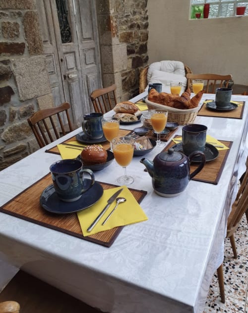 Table du petit-déjeuner aux Forges Du Lou avec croissants, jus d'orange et théières noires à Jugon-les-Lacs, France