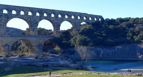 Promenade au Pont du Gard, monument historique entouré de nature et rivière scintillante.
