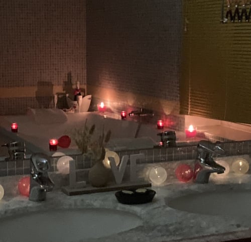 Ambiance romantique à la baignoire du Château de Ré avec bougies, pétales de roses et bulles à Le Petit Pressigny