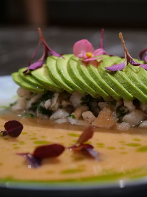 Rouleau de sushi gourmand à l'avocat avec microgreens et fleur rose en garniture chez Organica Yoga Shelter, Paquera