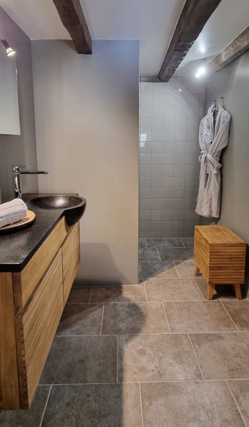 Modern bathroom at Moulin Renaudiots with wooden vanity, black sink, tile shower, and heated towel rack