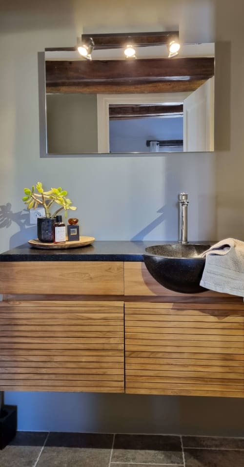 Modern bathroom vanity at Moulin Renaudiots with black stone sink, wooden cabinetry, and illuminated mirror in Autun.