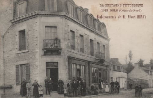 Bâtiment breton historique de 1918 à Dolo avec toit mansardé, devanture et visiteurs en costumes d'époque devant Les Forges Du Lou