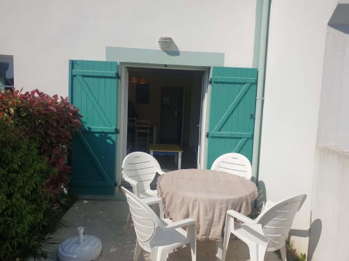 Volets turquoise et mobilier de patio blanc avec nappe beige à l'appartement Locmaria Belle Île-en-Mer
