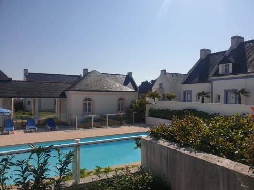 Résidence Loc'Maria à Belle-Île-en-Mer avec appartements modernes blancs, toits d'ardoise et piscine étincelante d'eau bleue