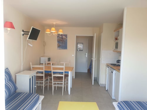 Appartement ouvert à Loc'Maria, Belle Île-en-Mer avec table à manger, cuisine, sièges rayés et TV murale