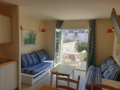 Appartement lumineux à Locmaria Belle Île en mer avec lits jumeaux, coussins rayés, lampes rouges et accès à la terrasse