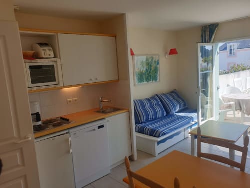 Studio cosy à Loc'Maria Belle Ile avec kitchenette, canapé-lit bleu rayé et accès à la terrasse