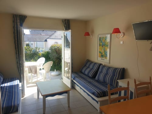 Séjour lumineux avec canapé rayé, coin détente et portes-fenêtres donnant sur la terrasse - Locations Loc'Maria, Belle