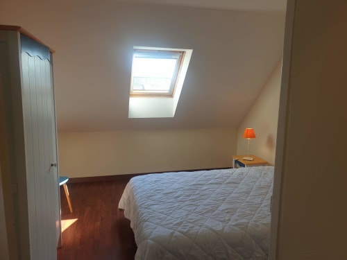 Chambre mansardée à Loc'Maria Belle Île-en-Mer avec lucarne, lit king-size, parquet et lampadaire orange
