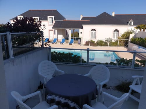Terrasse avec coin détente au bord de la piscine de l'appartement Loc'Maria Belle Île en Mer, vue sur la piscine et la propriété côtière