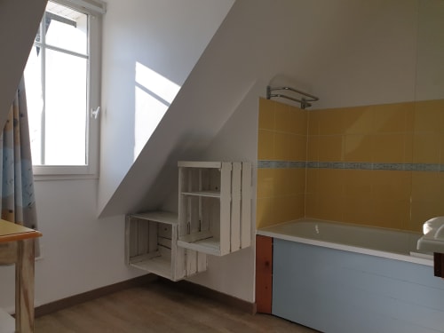 Salle de bain mansardée à Locmaria Belle Île en Mer avec carrelage jaune, baignoire et lucarne