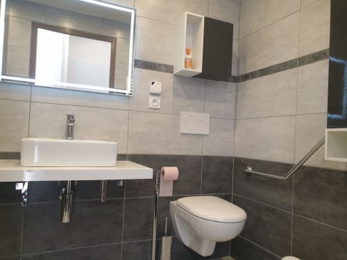 Salle de bain moderne avec lavabo blanc, toilettes et murs carrelés à l'appartement Loc'Maria Belle Île en Mer à Locmaria, France