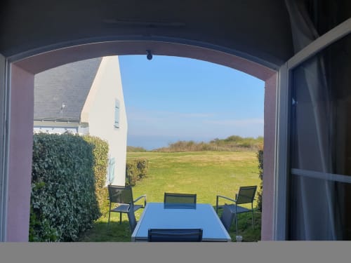 Vue mer depuis l'appartement Loc'Maria à Belle-Île-en-Mer, salle à manger avec table bleue surplombant la pelouse