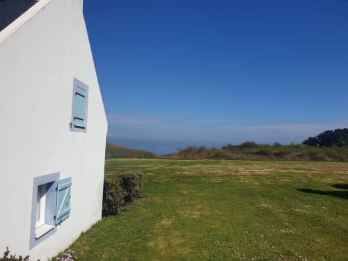 Immeuble blanc avec vue sur mer, prairie verdoyante et océan à Loc'Maria, Belle Île en Mer, Bretagne